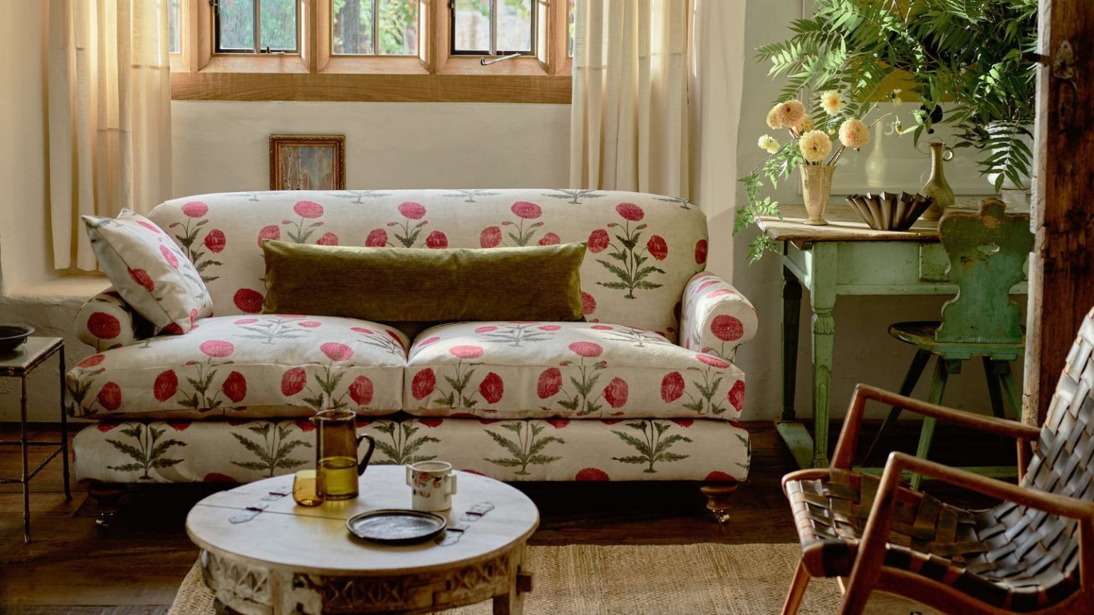 Je déteste voir des bacs de rangement en plastique laids sous mes canapés tous les jours, alors je passe plutôt à ces magnifiques bacs de rangement en jacinthe Poppy print sofa in cottage living room. There is a mid-century painted sage wooden sideboard with fresh leaves and flowers on, as well as a mid-century single chair and round distressed small coffee table