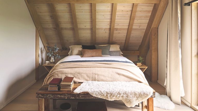 Barn extension decorated with a stylish Scandi feel. Bedroom in attic with wooden walls and double bed.