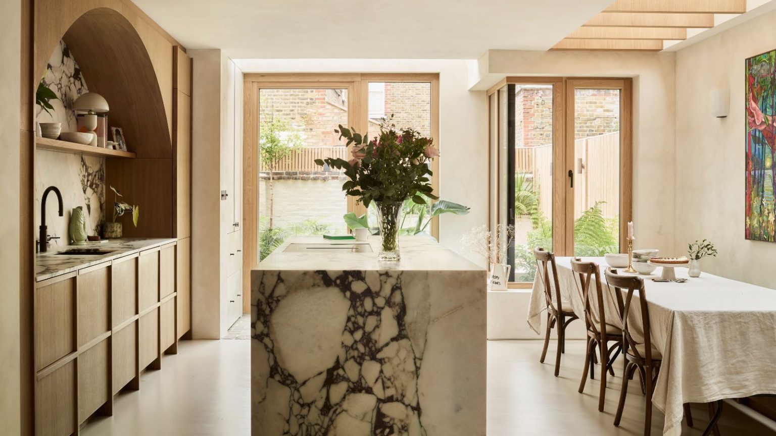 La méthode d’organisation « Calm Limit » m’aide à garder ma maison bien rangée sans perfectionnisme ni submersion An airy kitchen diner with a large marble island separating worksurfaces and a rectangular dining table with three chairs pulled up to it.