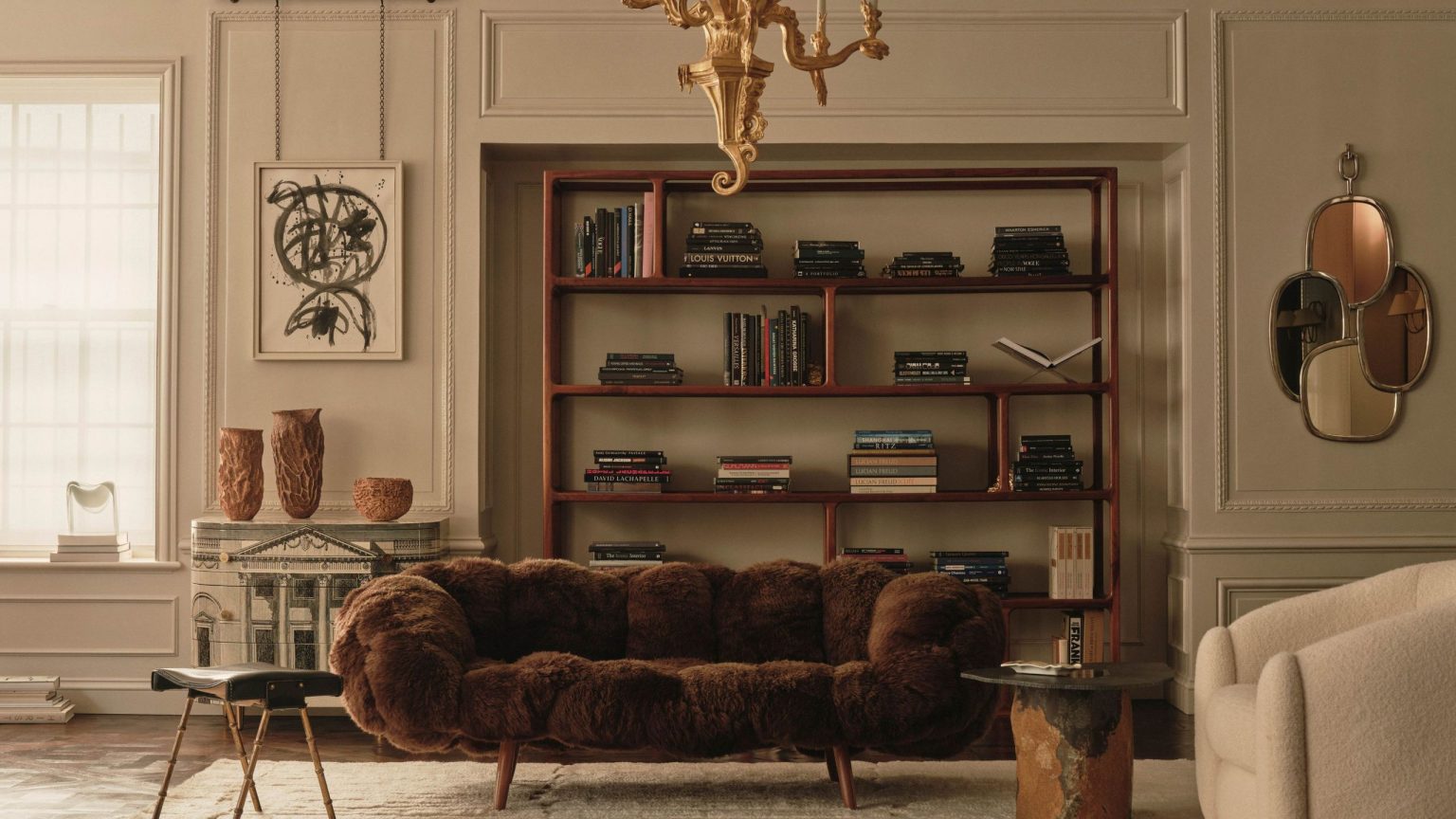 Le pouvoir de la texture dans le design d’intérieur – 6 façons dont les designers l’utilisent pour façonner l’apparence (et la sensation) de chaque pièce Cream living room with paneled walls and modern furniture, including a brown furry couch, a wooden minimalist bookcase and a cream bouclé arm chair