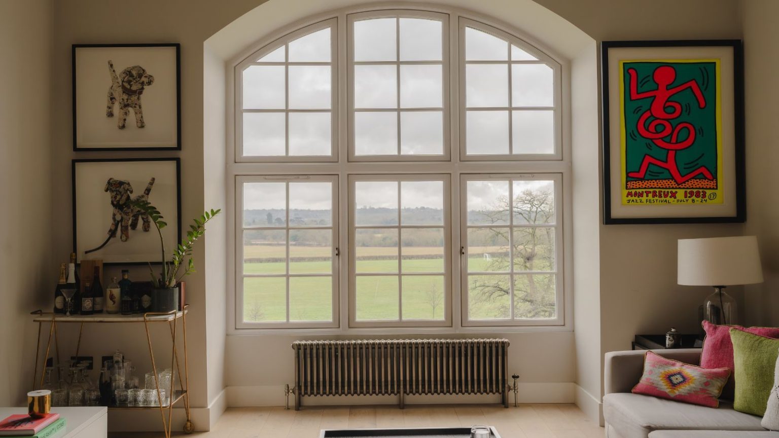 Je parie que vous ne saviez pas que vous êtes censé nettoyer cette petite partie de la fournaise – Sautez-la et vous pourriez perdre de la chaleur pendant la nuit la plus froide A small baseboard radiator, mounted under a very large arched window in a living room, overlooking green fields.