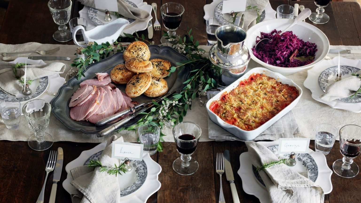 « Quelques passes les ramènent à l’affûtage parfait » – Des chefs professionnels révèlent les 3 choses qu’ils utilisent pour aiguiser facilement les couteaux pour les fêtes de fin d’année A Thanksgiving, Christmas tablescape for a dinner party, with a white table runner on a brown wooden table, sliced ham, pastries, red cabbage, vintage plates, white napkins, silver flatware, and wine glasses filled with red wine.