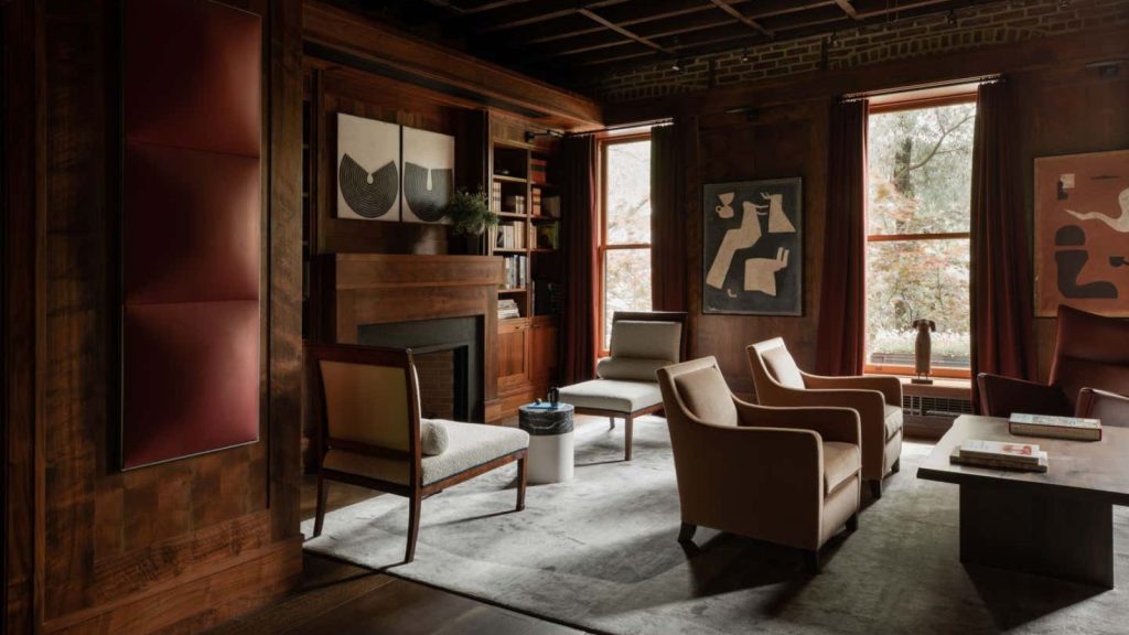 A deep red painted living room with two separate seating areas. Wood panelling on the walls.