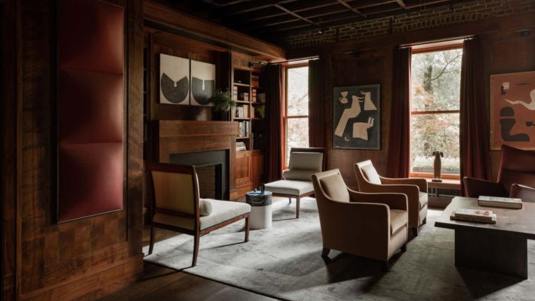 A deep red painted living room with two separate seating areas. Wood panelling on the walls.