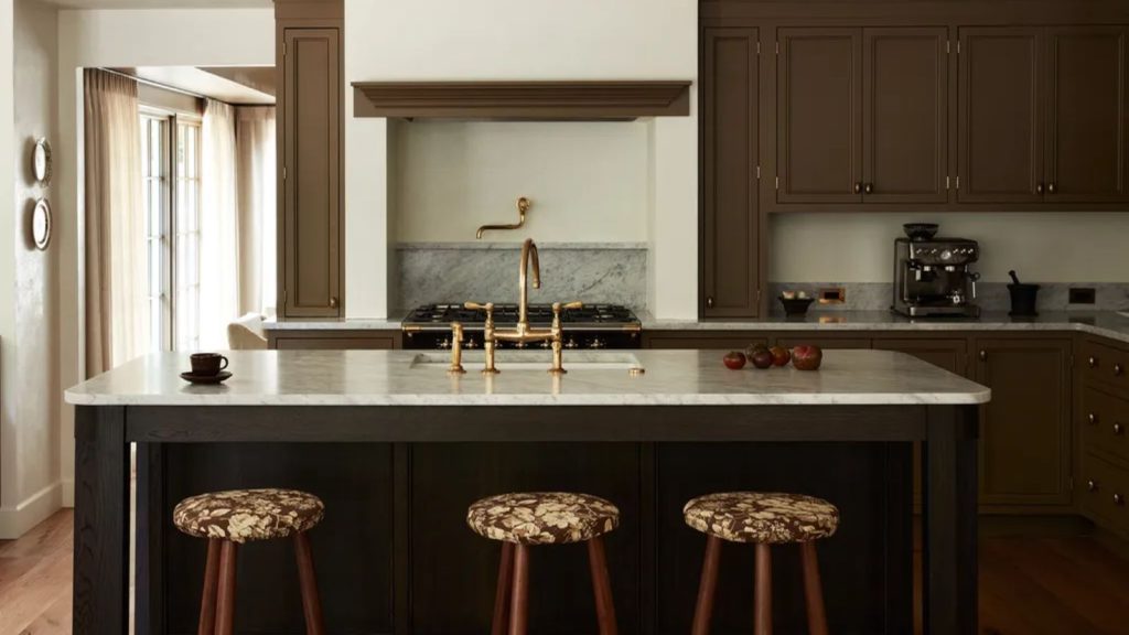 Ces 5 secrets de préparation d’un chef professionnel changeront votre façon de préparer les repas des fêtes – c’est la configuration en coulisses dont chaque hôte a besoin A kitchen with brown painted cabinets and white marble countertops. Gold fixtures