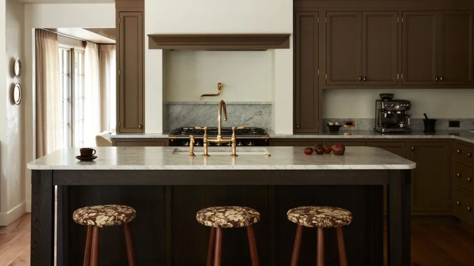 La raison surprenante pour laquelle votre poêle à induction bourdonne – et la solution simple que la plupart des gens manquent A kitchen with brown painted cabinets and white marble countertops. Gold fixtures