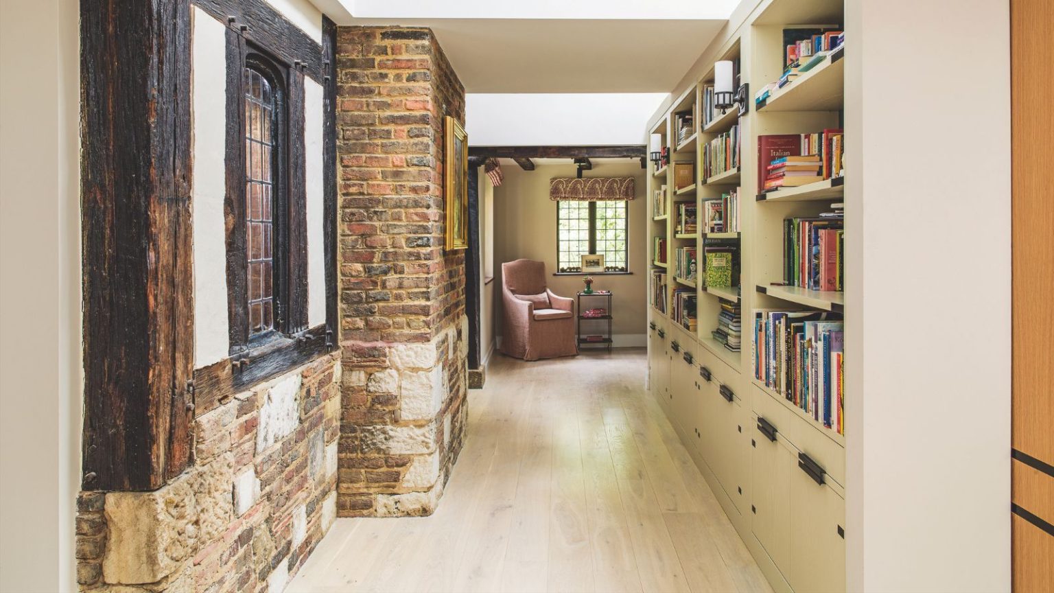 « Sauter les frais d’abonnement tout en sécurisant ma maison avec d’excellentes fonctionnalités, c’est comme une arnaque à la vie » – la sonnette vidéo Eufy E340 ne coûte désormais que 89 $ A library hallway space with bookshelves down one side, and an exposed brick wall on the other side with a Tudor-style window. At the end of the corridor is a pink upholstered chair under a window.