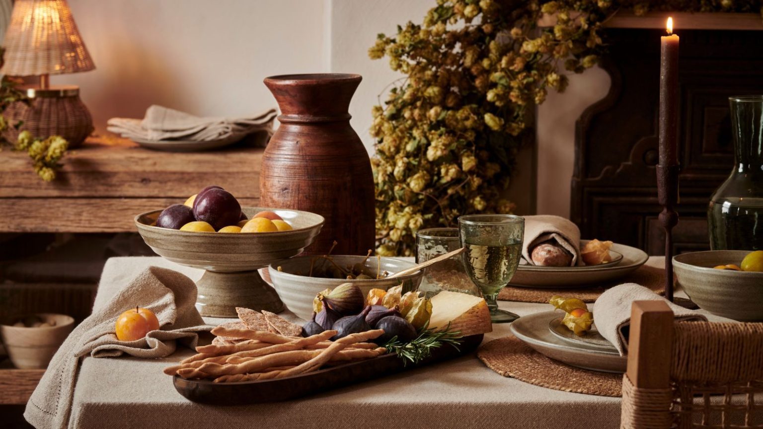 Vous n’avez pas besoin de plastique pour conserver la fraîcheur des produits d’automne – Ces 5 astuces de conservation garderont vos légumes croquants et savoureux A fall dining table laden with seasonal food in stoneware dishes.