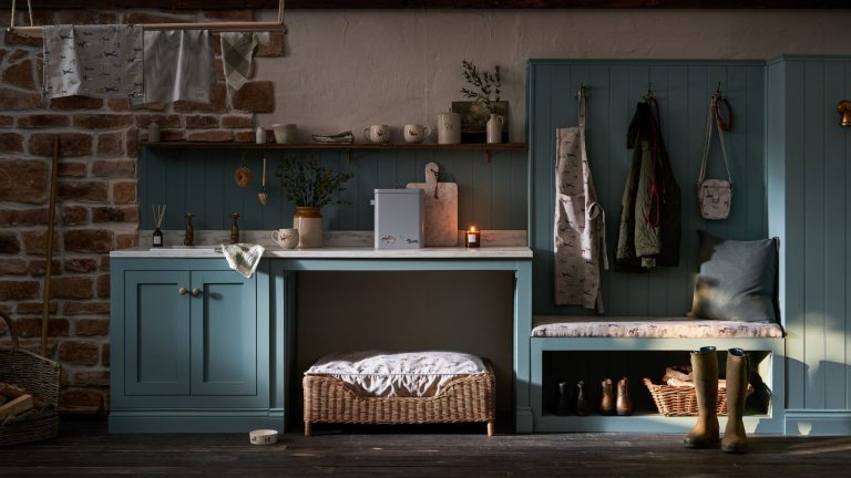 Ces « blocs du ciel » aromatiques et non toxiques à 11 $ sont une arme secrète naturelle contre les mites cet automne – les acheteurs adorent leur « bon parfum » A blue boot room with exposed brick walls, brown wooden flooring, shelving, a dog bed, coats hanging up, green wellies, a lit candle, and laundry hanging up high to the top left.