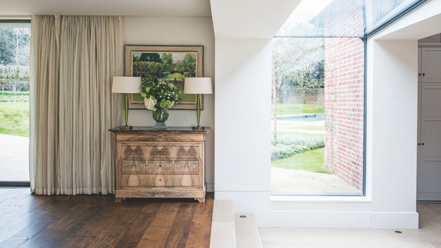 « Les propriétaires d’animaux en ont besoin » – cet outil de nettoyage de plinthes à 19 $ maintient les maisons occupées « propres et sans poussière », selon les acheteurs Bright transitional space with glass windows, wooden flooring, white walls, and a brown chest of drawers with two matching lamps with white shades, an artwork above, and cream curtains to the left.