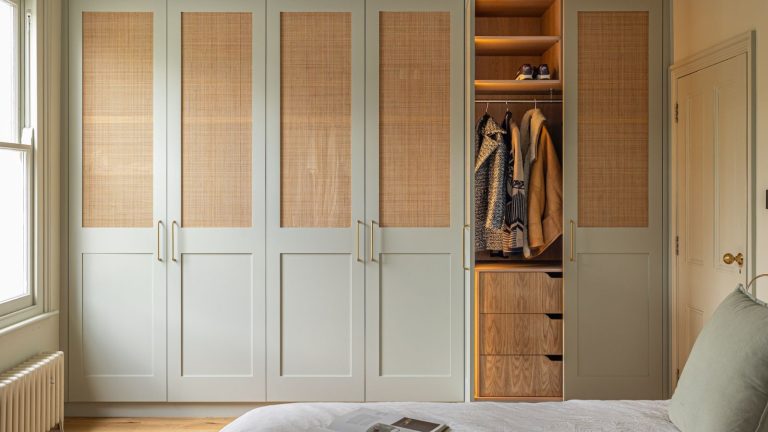 J’ai essayé la règle de désencombrement cinq-cinq pour arrêter l’encombrement des placards avant même qu’il ne commence – je suis choqué que cela fonctionne A blue built-in closet with rattan window panels. One door open showing a hanging rail and drawers beneath.