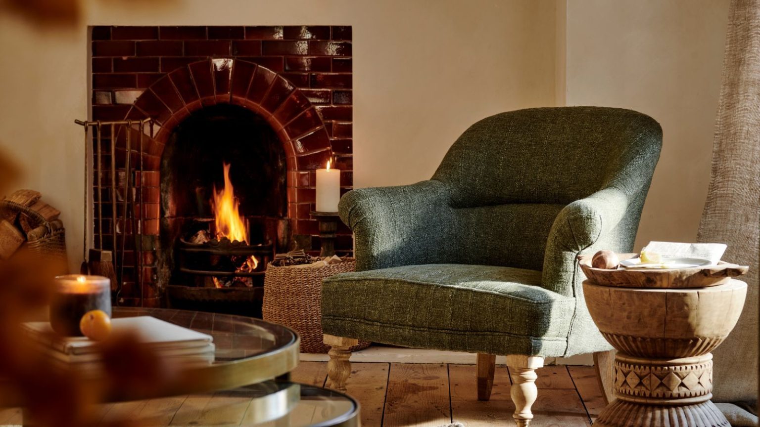 Combien d’heures par jour votre chauffage doit-il fonctionner ? HVAC Pro révèle le programme Boucle d’or d’hiver qui équilibre confort et efficacité An upholstered green armchair beside a brick fireplace in a cream living room.