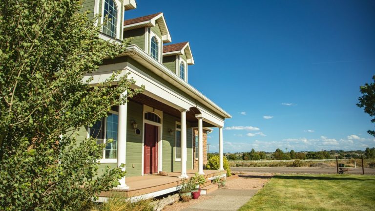 Si vous n’effectuez qu’une seule tâche d’entretien cet automne, donnez un peu d’attention à vos gouttières – cet outil à 19 $ le rend plus rapide et plus facile. A green painted suburban American home with a lawned front yard, and a view of fields and trees.