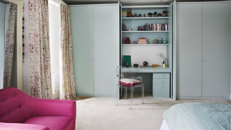 « Si vous détestez creuser pour trouver des trucs, c’est une victoire » – vous en avez marre que votre vanité soit en désordre ? Ces organisateurs à 72 cents sont une solution instantanée Small bright bedroom with hidden vanity in the built-in closet. There is shelving above the vanity and clear plastic chair. The room has a large window with floor length floral curtains and a bright pink accent chair