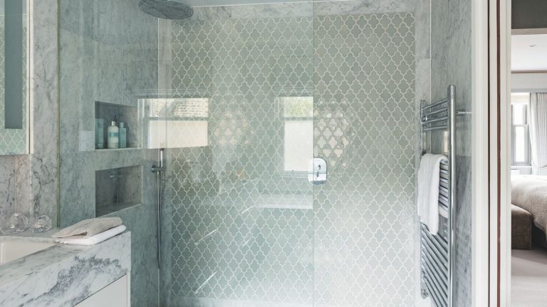 « J’étais sceptique, mais ça marche » : ce détachant anti-moisissure le plus vendu à 18 $ nettoie, désodorise et rafraîchit facilement A marble and glass tiled shower with a shower niche, large glass screen, silver radiator and marble sink