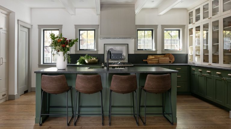 3 raisons pour lesquelles vous devriez nettoyer vos sols avec de la cannelle cet automne, selon les spiritualistes et les nettoyeurs forest green kitchen with black quartz countertops, hardwood floor, leather bar stools, glazed counter units, black faucet, island with sink