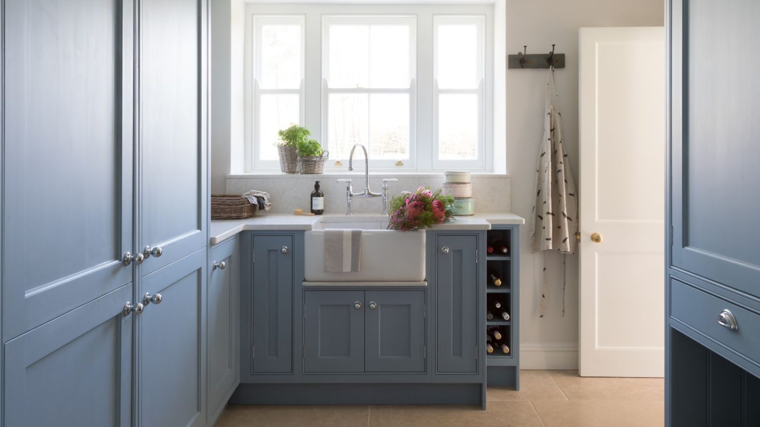 C’est le seul héros de lessive à 9 $ dont vous avez besoin pour empêcher la literie d’hiver de s’accumuler dans la sécheuse – cela réduira même également votre facture d’énergie. A utility room with blue built-in cabinets and a white farmhouse sink beneath a large framed window.