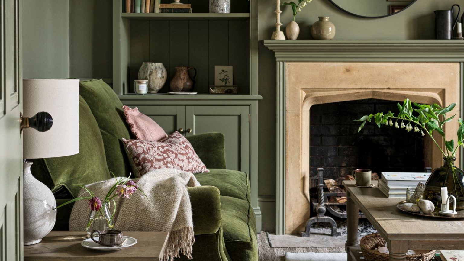Le défi facile de désencombrement du Nouvel An en 5 jours que vous pouvez commencer dès maintenant – et éviter le chaos d’ici lundi soir A green color-drenched living room with a deep green velvet sofa against the wall. Pink throw pillows. A light wood coffee table in front of it.