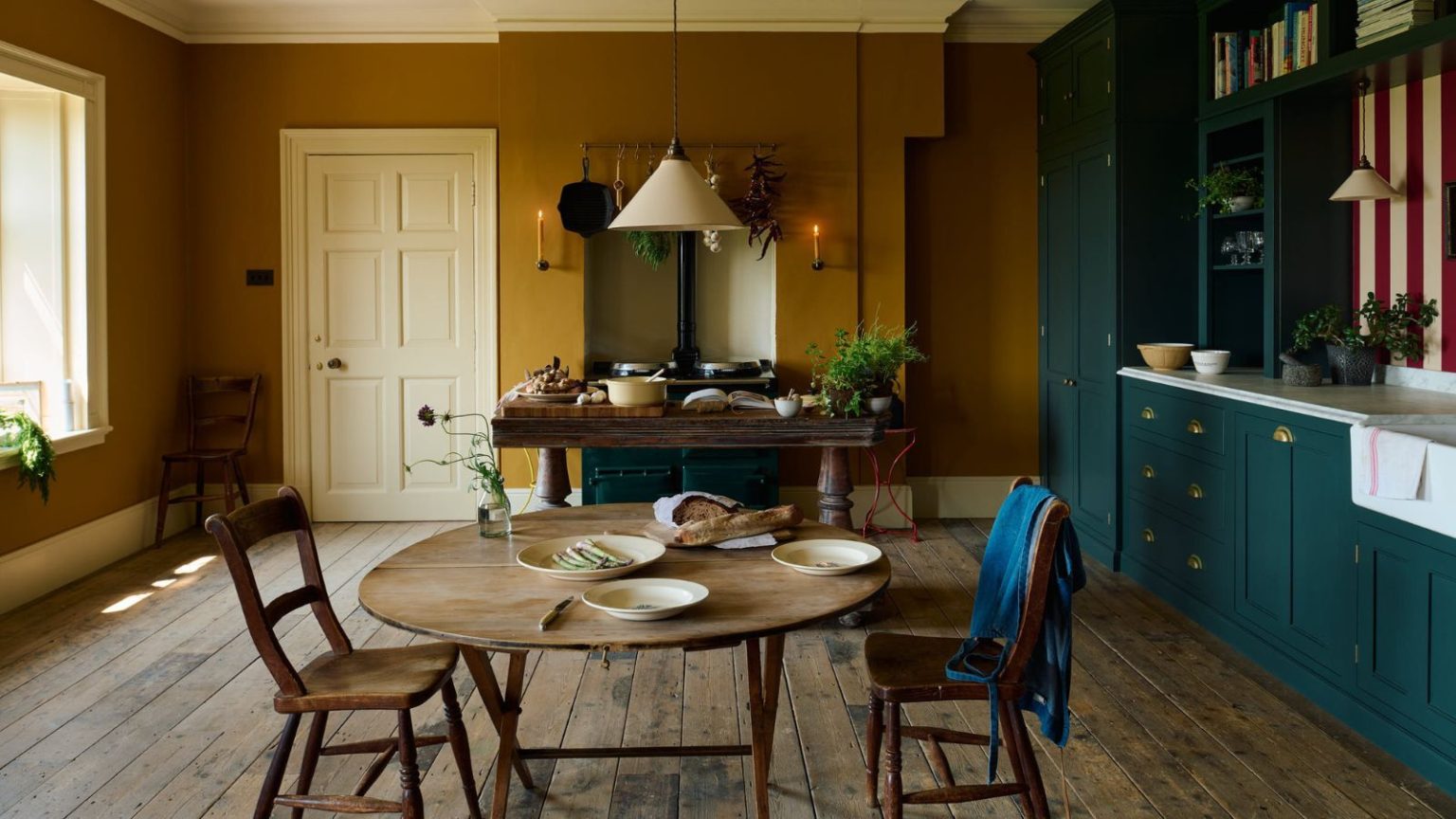 « Je l’utilise pour tout nettoyer ! » – Walmart vend un aspirateur sec/humide à 85 $ que les professionnels du nettoyage ne jurent que par pour seulement 30 $ ce Cyber Monday Mustard yellow and dark blue kitchen diner with hard floors and striped red and white backsplash. There are units on the right, and a window to the left, with a table in the background alongside a range cooker inset in an alcove
