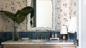 La seule chose qui manque à votre salle de bain cet hiver – les designers disent que c’est la réponse simple à un espace plus confortable, plus chaleureux et plus accueillant A close-up of a wooden bathroom vanity with a marble countertop decorated with a vase of leaves and a gold lam