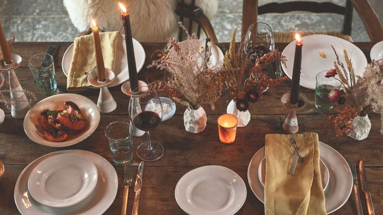 Les pros révèlent où ne jamais placer de bougie parfumée dans votre maison lorsque vous recevez des invités pour un dîner – et quoi utiliser à la place pour l’ambiance An autumnal tablescape with glasses, plates, candles and dried flowers.