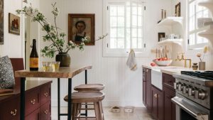 Un agencement intelligent, des idées de rangement géniales et une palette de couleurs audacieuses ont transformé cette cuisine orange démodée en un délice de chalet confortable A cottage kitchen with white paneled walls, burgundy cabinets, wooden countertops, and a cozy eat-in area