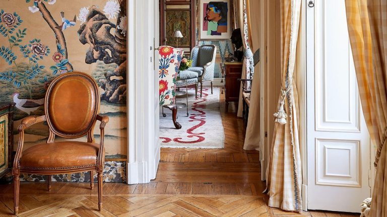 Layered entryway with wooden floors, vibrant wallpaper and leather chair