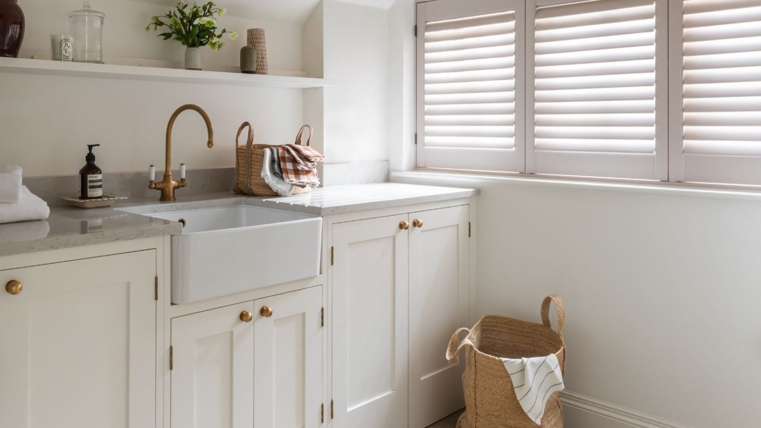 Bright neutral laundry room with shutters and woven basket