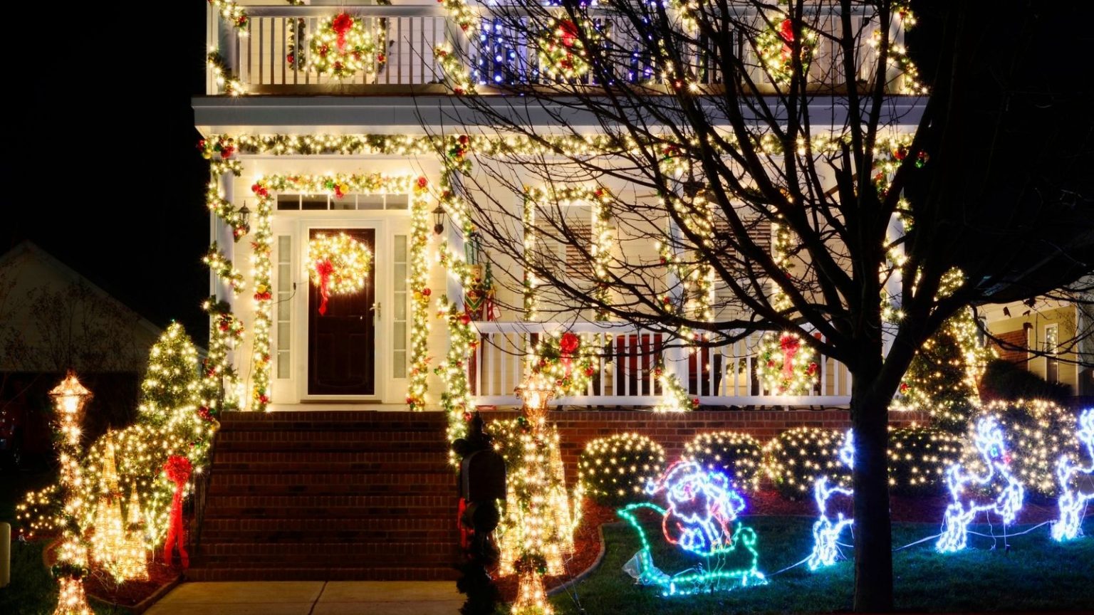 Définissez la couleur de la lumière de Noël extérieure et synchronisez-la avec la musique de votre téléphone à moindre coût avec les guirlandes lumineuses personnalisables à 79 $ de Philips Hue. Shot of home exterior with bright, multi-colored Christmas lights, against nighttime background.