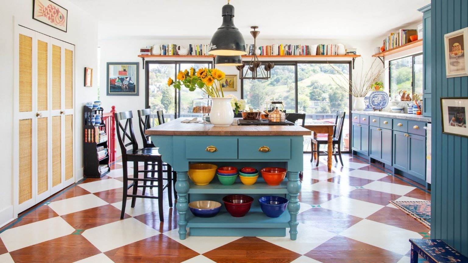 Posez les carreaux en damier – Tous les décorateurs les plus chics que je connais peignent plutôt ce motif classique sur le sol en bois de leur cuisine. A large kitchen with blue cabinets and a painted wooden checkerboard floor design