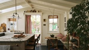 A new kitchen extension with vaulted paneled ceilings, olive green cabinets, marble countertops, and a cozy eat-in area