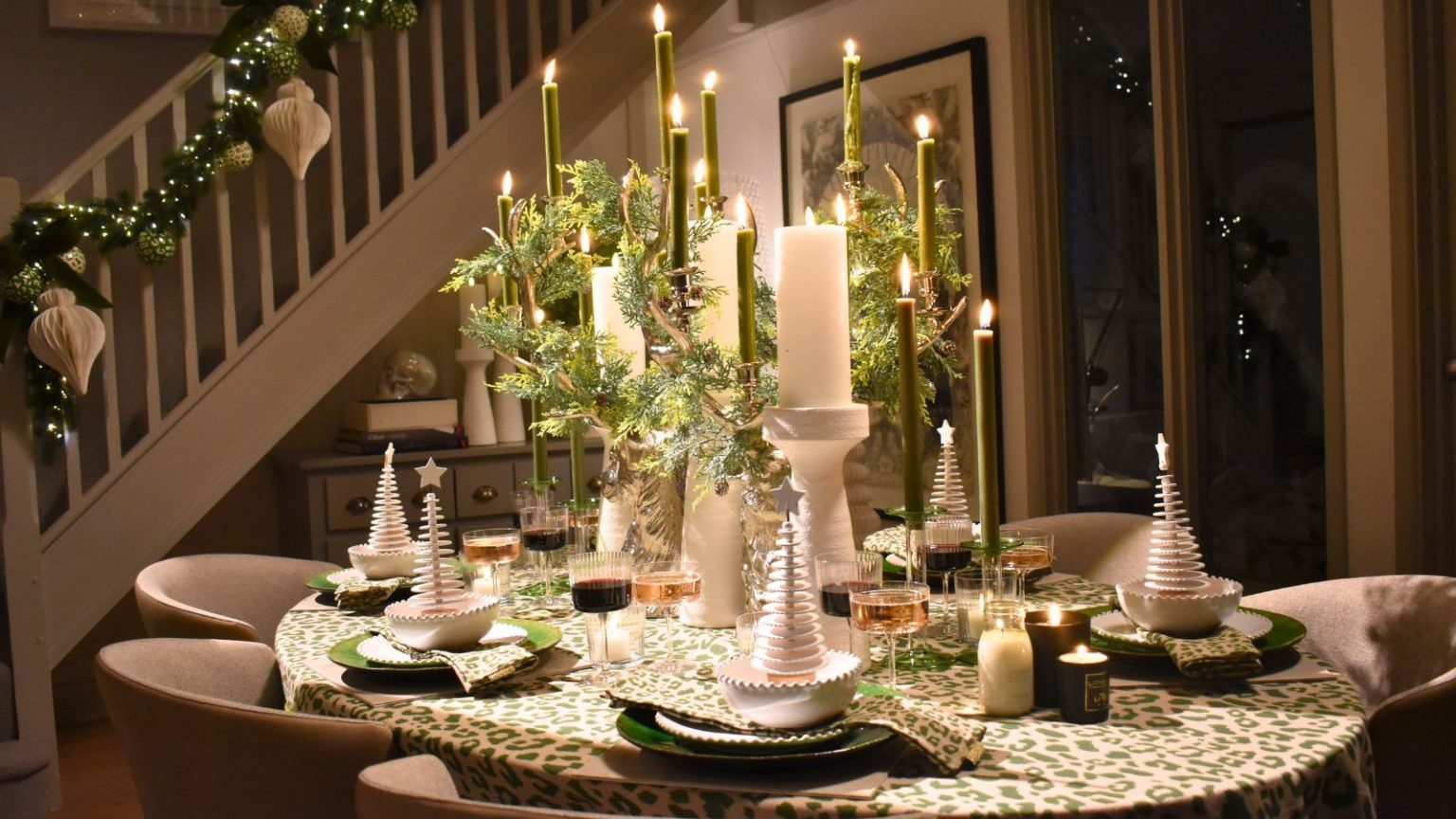Je cache les dégâts de mon évier aux invités de Noël avec un égouttoir japonais enroulable « sophistiqué » à 40 $ qui est un joyau pour les petits espaces Pretty Christmas tablescape in compact open plan home with staircase in background. The table has a green and cream theme, with large church candles and ivy