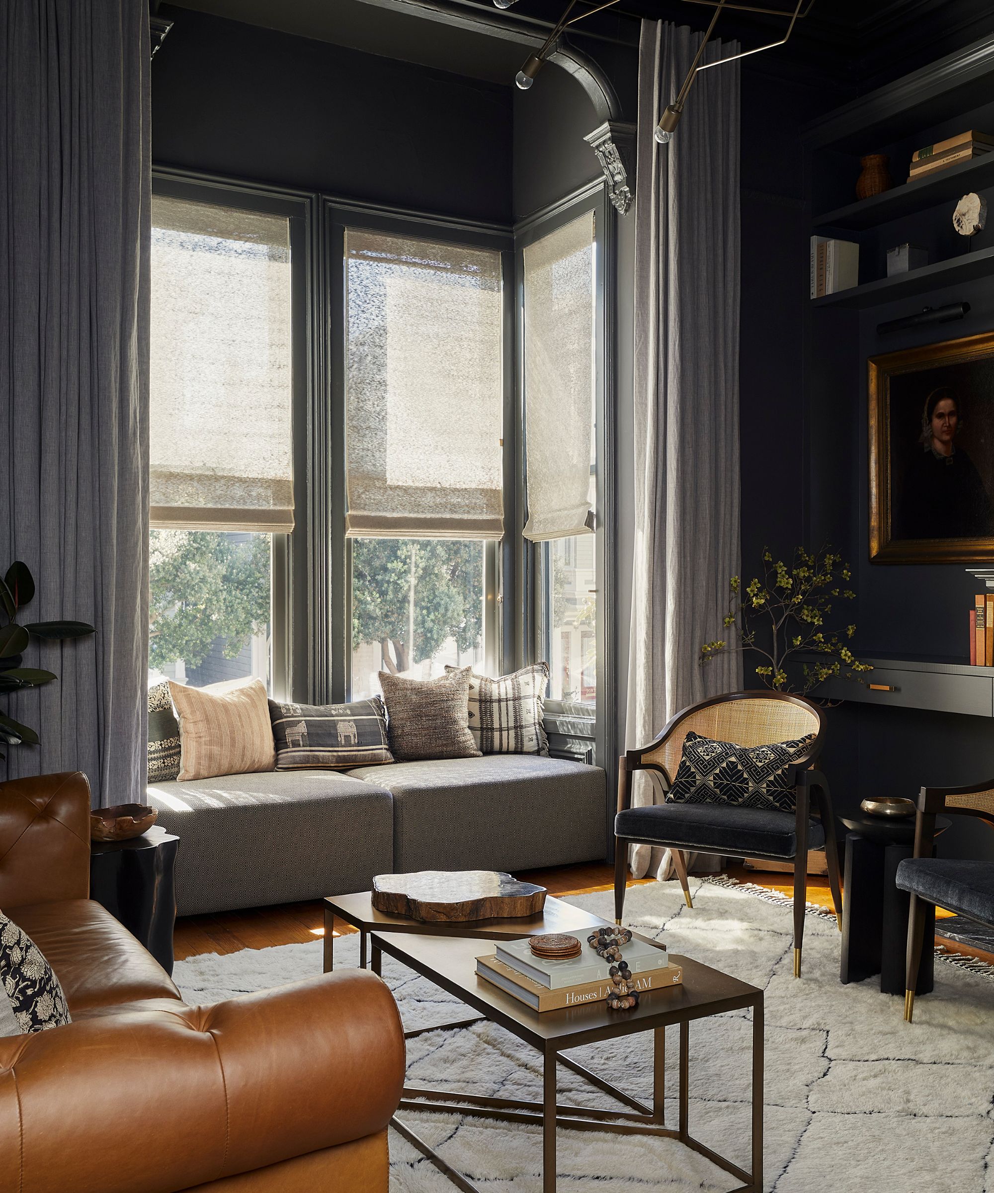 Salon sombre et maussade avec un canapé en cuir marron, un siège près de la fenêtre et une chaise tressée