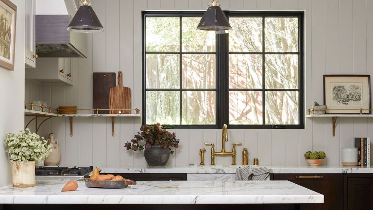 Un appartement victorien de 1895 passe du traditionnel au transitionnel avec des portes coulissantes secrètes, de la peinture noire fumée et d’anciens objets de famille White kitchen with marble top and dark cabinets