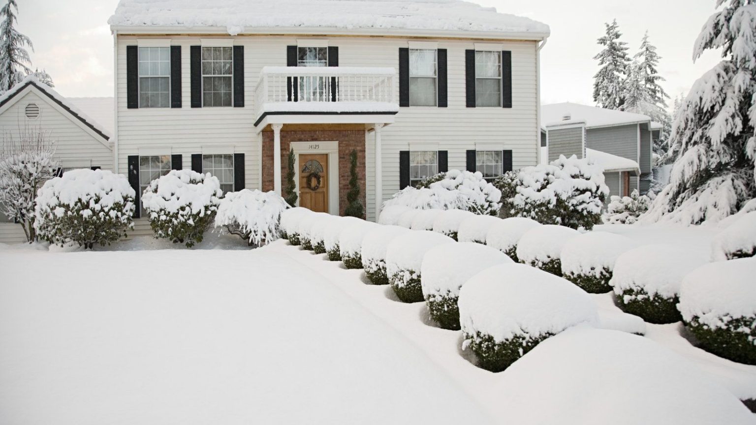 Souffleuse à neige ou pelle à neige : comment décider quel outil de déneigement convient le mieux à votre cour cet hiver A white two-storey house and front garden covered in a thick layer of snow