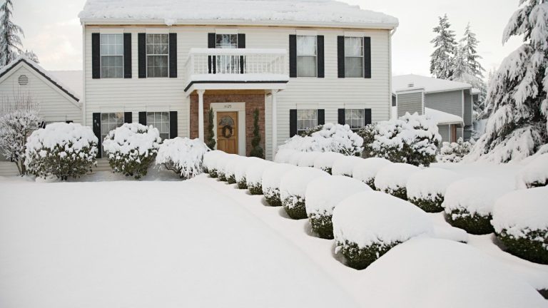 Souffleuse à neige ou pelle à neige : comment décider quel outil de déneigement convient le mieux à votre cour cet hiver A white two-storey house and front garden covered in a thick layer of snow