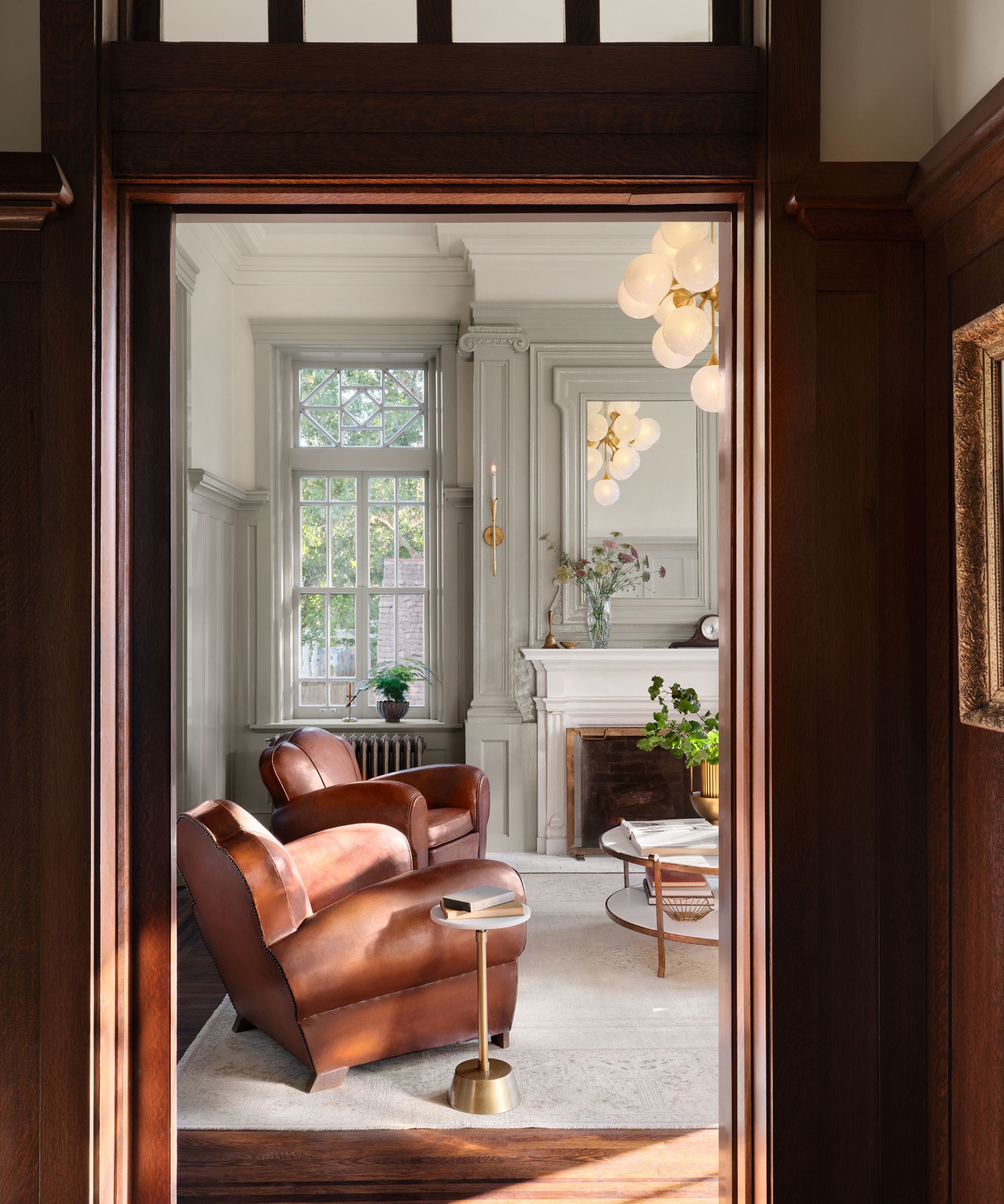 Couloir lambrissé donnant sur le salon avec fauteuils en cuir marron