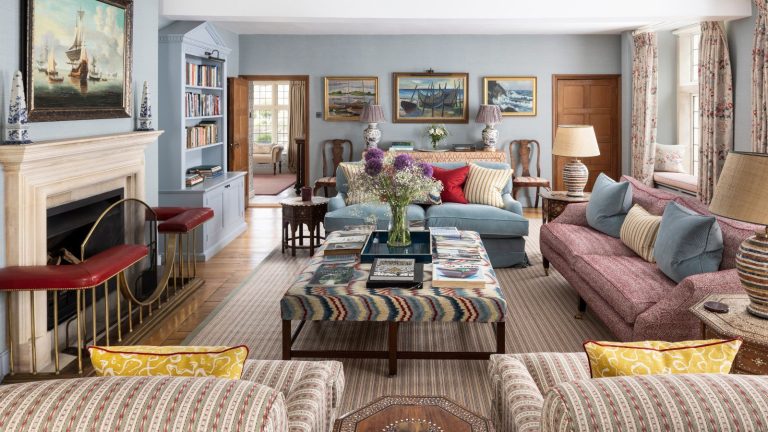 traditional powder blue living room with eclectic English style, a fireplace, upholstered ottoman and mismatched patterned sofas and armchairs