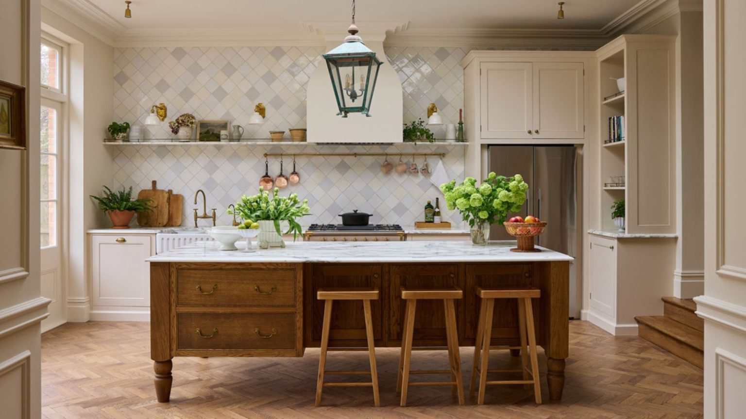 J’ai demandé aux architectes d’intérieur de prédire les plus grandes tendances en matière d’armoires de cuisine de 2026. Voici les 9 looks qui, selon eux, prendront le dessus A warm neutral kitchen with cream cabinets, a wooden island, marble countertops, and a tiled backsplash