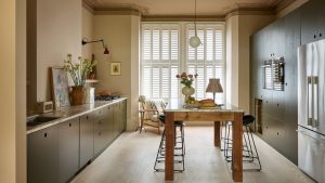 Par quoi remplacer les armoires de cuisine Sage Green ? C’est la teinte la moins utilisée dont les concepteurs ne peuvent pas se lasser. A galley kitchen with warm neutral walls, green cabinets, and a wooden freestanding kitchen island