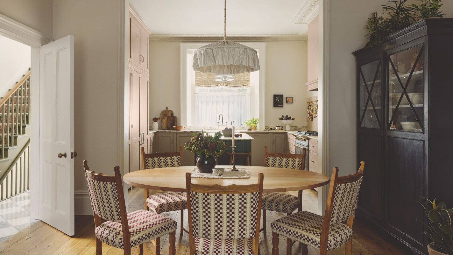 16 choix d’organisation IKEA abordables que nos éditeurs de désencombrement adorent lors de leurs rares soldes d’hiver – Réinitialisez toute votre maison en toute simplicité A cozy dining room with a round wooden table and five chairs. A low hanging fabric pendant above it. A blue hutch storage cabinet to the right.