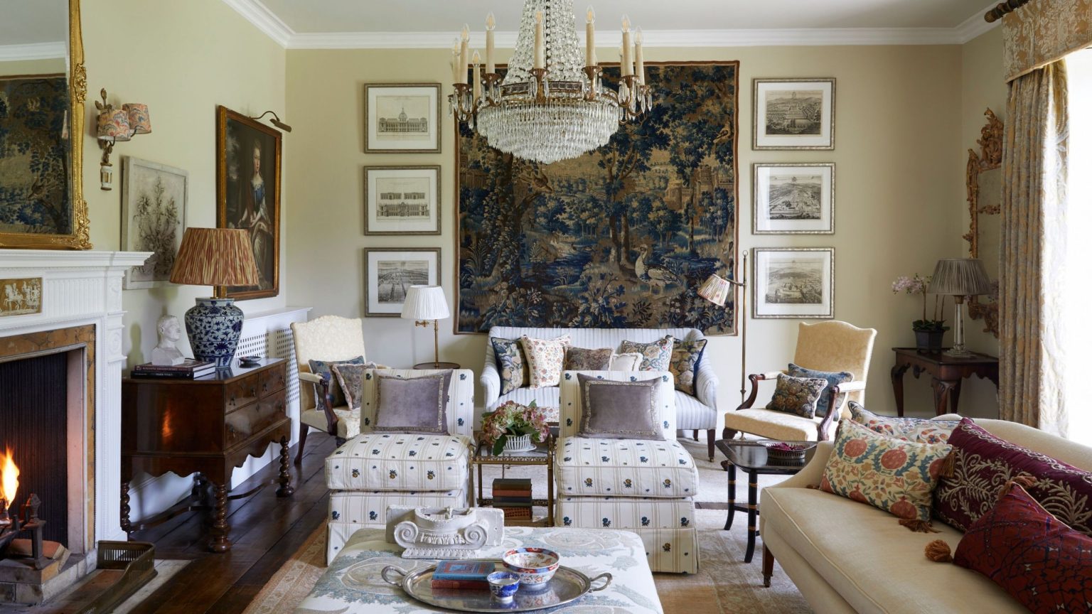 Better Vintage : « Un langage visuel en tissu » – Comment les tapisseries anciennes façonnent les pièces, pas seulement les surfaces A formal, traditional living room featuring a grand crystal chandelier, a large blue landscape tapestry, and a crackling fireplace