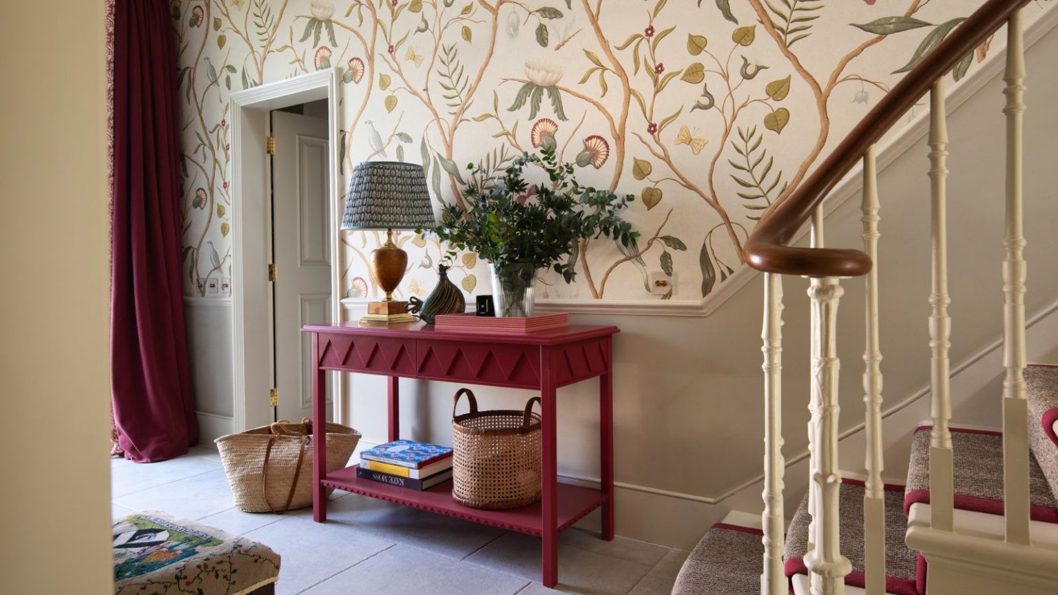 J’en avais marre du chaos dans mon placard sous les escaliers – Ces crochets à 83 cents ont triplé mon espace de stockage hallway with floral wallpaper above chair rail, stone painted underneath, red console and drapes, stone floor tiles, lamp, baskets, runner on stairs, Georgie Wykeham Designs