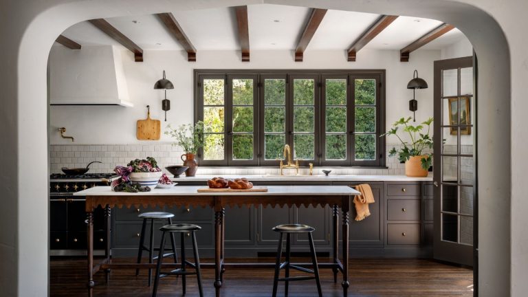 A kitchen with warm black cabinets, white walls, and dark wood floor and a kitchen island.