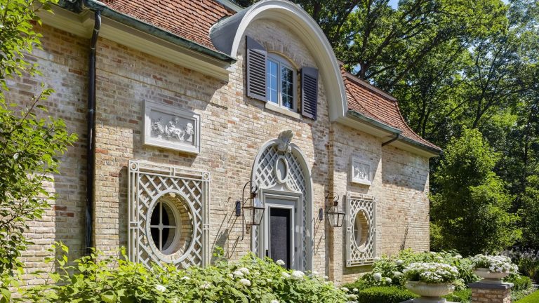 Alors que les livraisons à domicile au printemps augmentent, cette sonnette Philips « sans abonnement » est la protection ultime pour votre porche Historic building with brick exterior, round windows and detailed archway, surrounded by trees and greenery