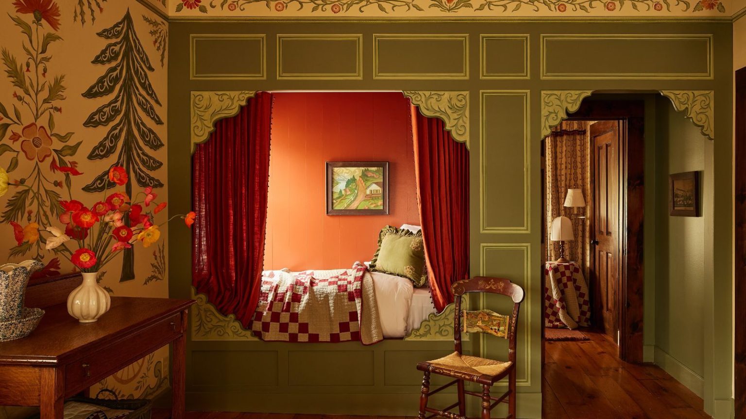 La courtepointe vintage de votre grand-mère est de retour à la mode – et j’ai trouvé les meilleurs endroits pour acheter votre propre version de qualité patrimoniale a room with a built in bed with curtains and a red and white quilt, a chair next to the bed, and a console table with a bouquet of flowers on it