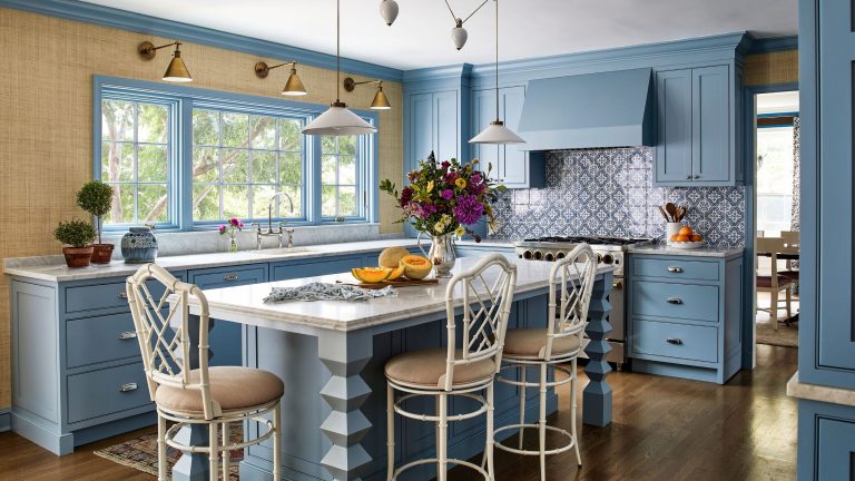 Comment ce designer a transformé une maison désuète qui « ressemblait à la maison originale de votre grand-mère » en un havre éclectique et coloré A blue kitchen with natural textured wallpaper