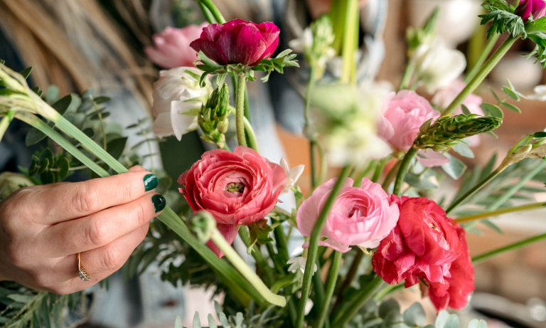 Pétales et racines : comment créer un arrangement floral symbolique – et accueillir la nouvelle année avec intention Hand placing narcissi into a vase of ranunculus and other flowers