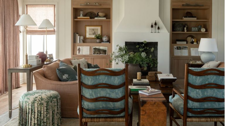 La formule simple d’équilibrage des couleurs de cet architecte d’intérieur m’a finalement aidé à planifier le schéma de toute ma maison – c’est la réponse à l’utilisation à la fois de tons neutres apaisants et de nuances audacieuses. farmhouse meets grandma chic aesthetic white living room with tongue and groove walls, light oak built in shelving, fireplace, soft pink couch, skirted floral ottoman and two dark wood armchairs with blue cushions