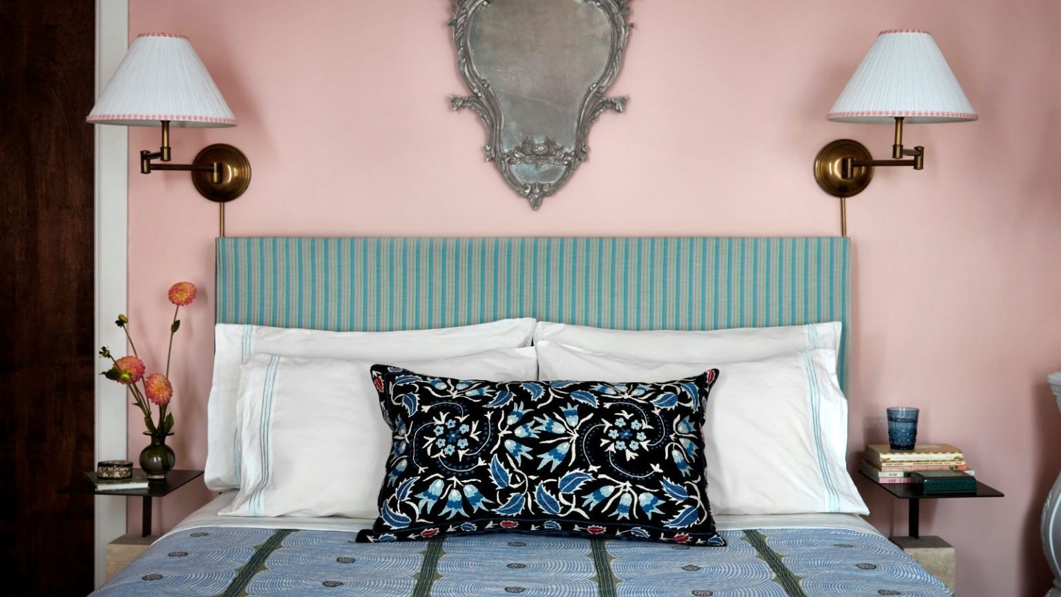 Le « test de seuil » sans culpabilité m’a aidé à désencombrer facilement mon placard d’hiver bien rempli en 5 minutes Blush pink painted bedroom with vintage-looking patterned blue bedding, striped green and cream headboard with paired brass wall lamps and an ornate wall mirror
